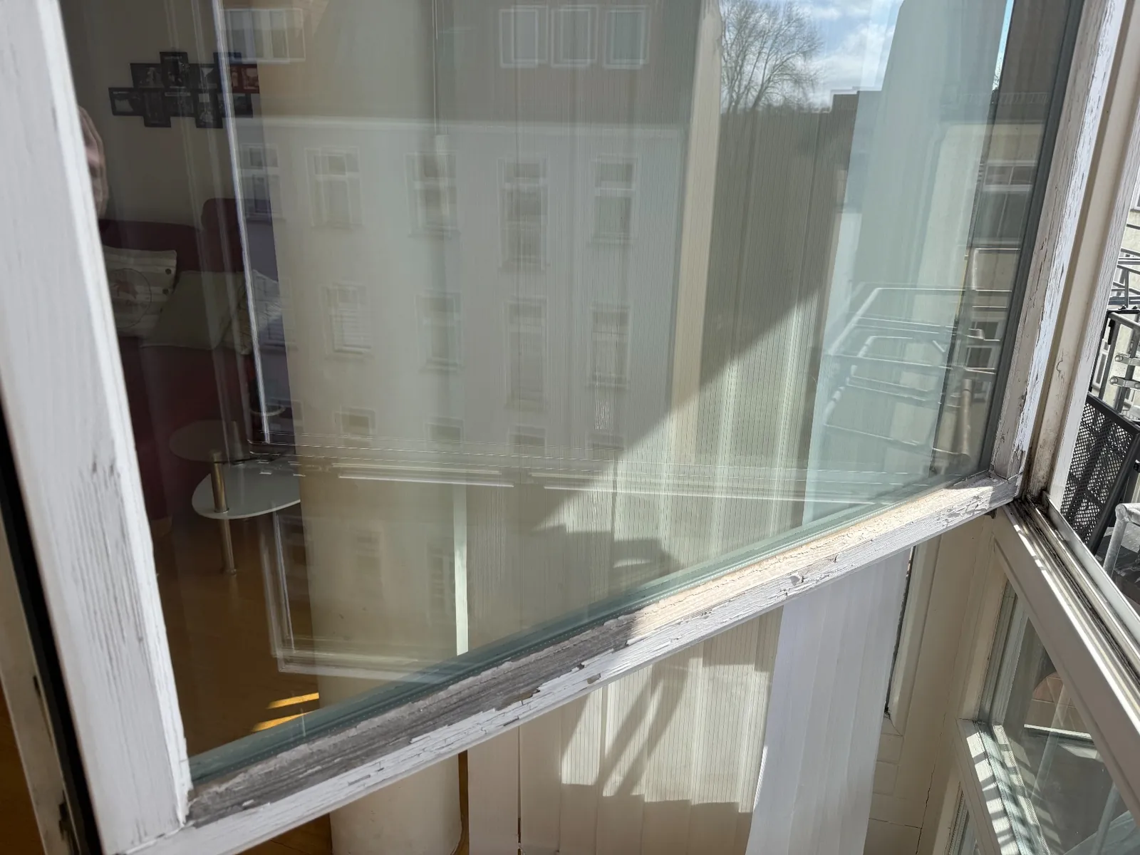 Verwitterter Fensterflügel mit blankem Holz vor der Fenstersanierung